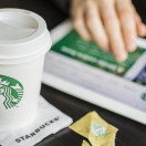 An entrepreneur views information about Starbucks on his tablet while drinking coffee