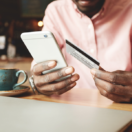 Man on cell phone holding credit card; SaaS pricing concept