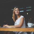 Young woman using laptop in coffee shop; digital customer experience concept