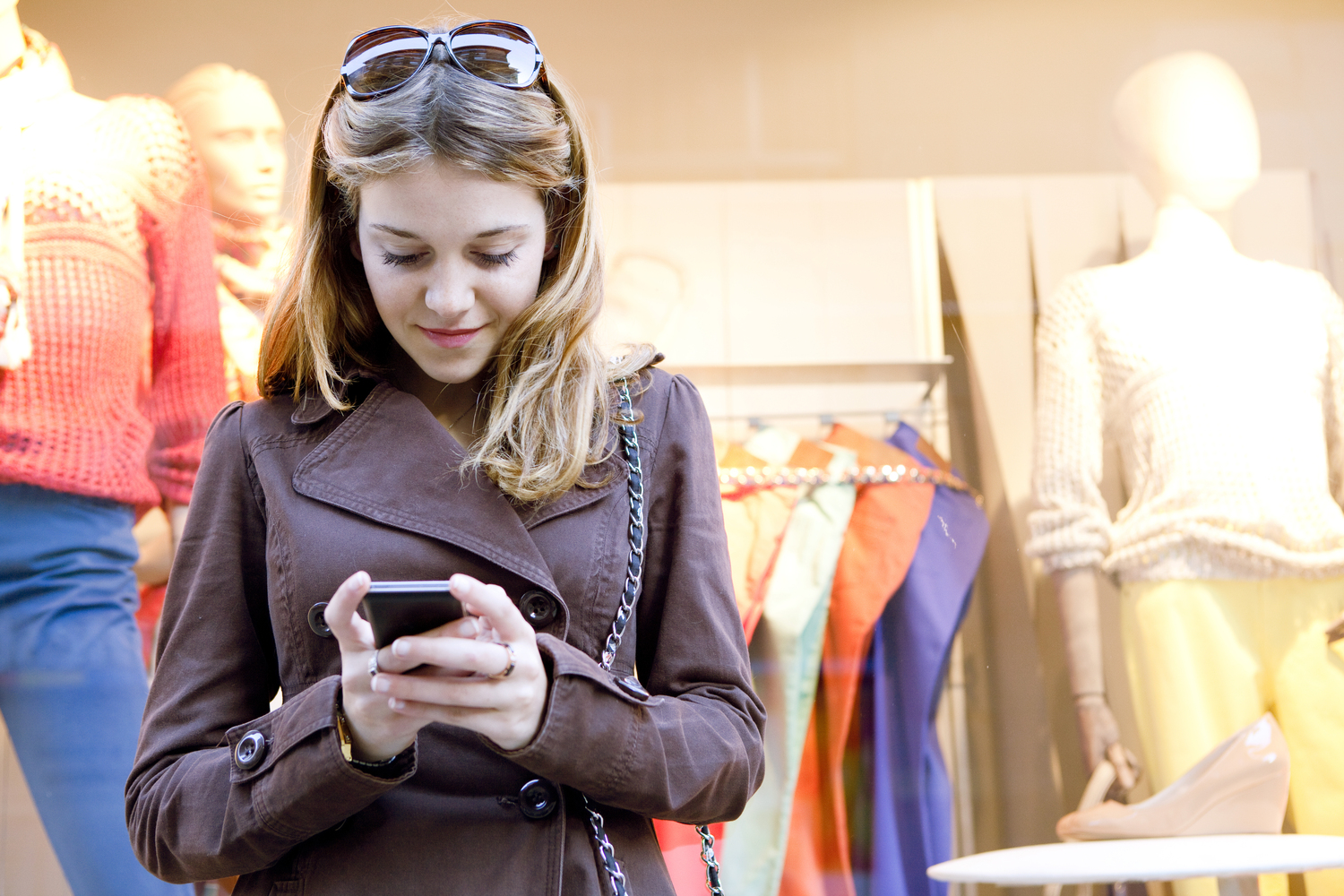 Girl on smartphone in front of clothing store