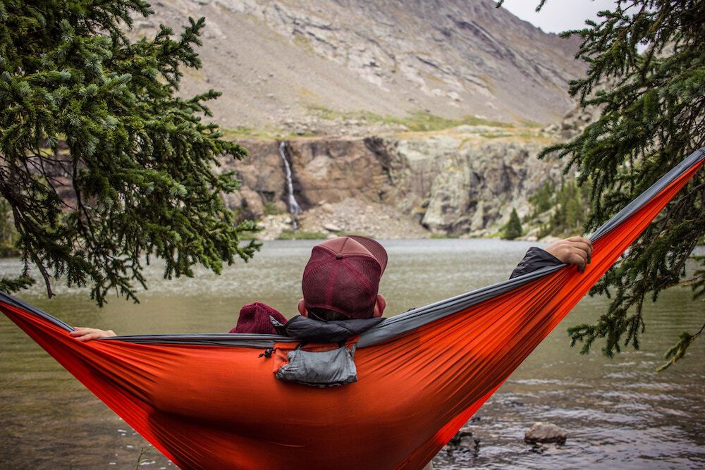 Man relaxing in a hammock while camping; work life balance concept