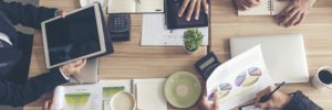 team of people work together at a table with computers and graphs